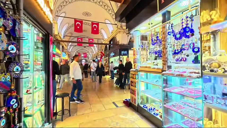 Historic Grand Bazaar entrance arch with shoppers and bag stalls in Istanbul