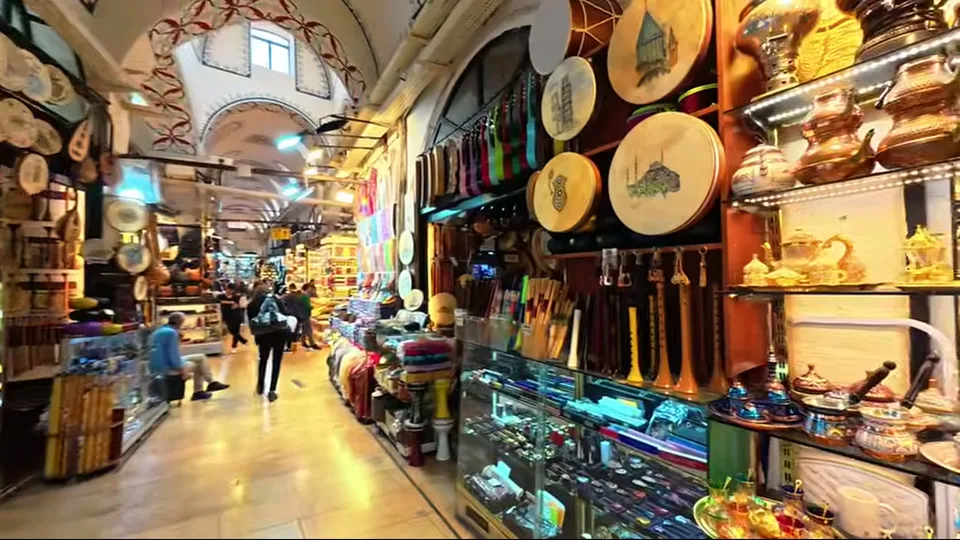 Wider Grand Bazaar corridor with Turkish flags, souvenirs, and antique-style stalls